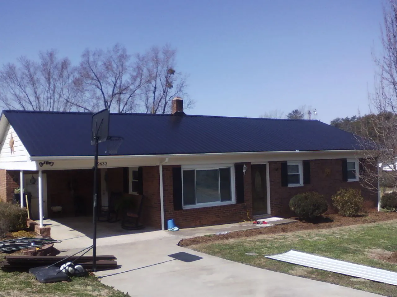 Finished dark blue metal roof on a brick ranch with a carport in Indianola
