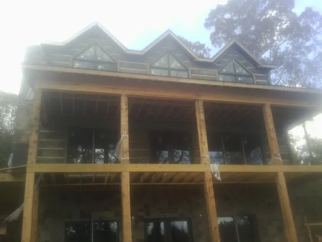 Dormers and porch framing on a large log home under construction — Roof Coating work by our crew in Indianola