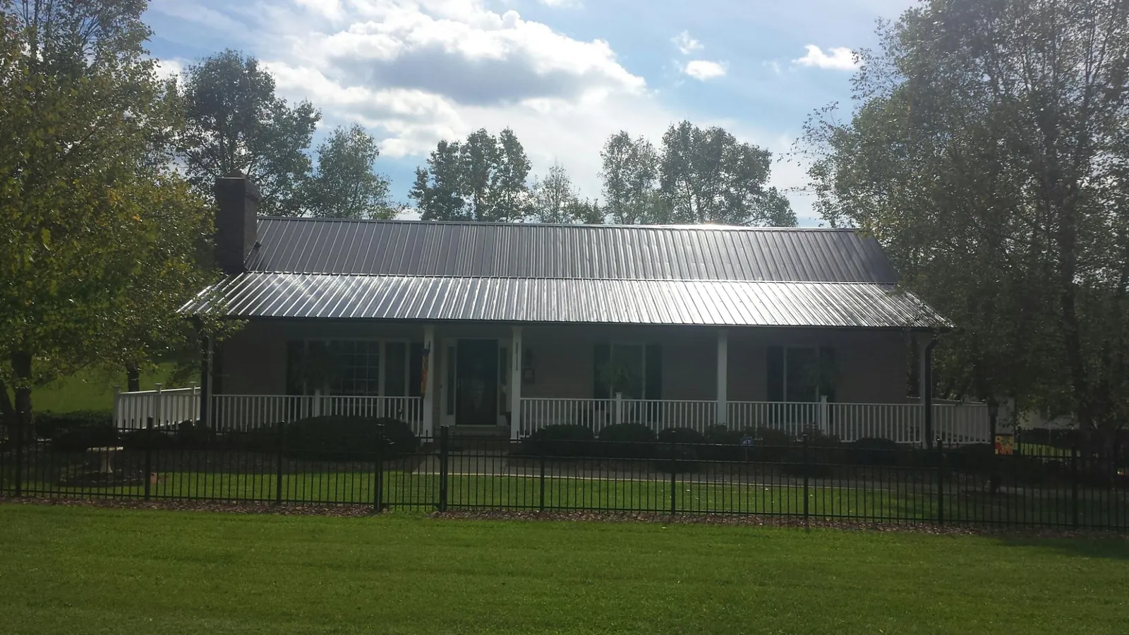 Gray metal roof on a brick ranch with a full width front porch — Gutter Guard Installation work by our crew in Indianola